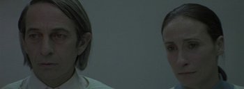 Movie still from “Post Mortem” (2010), directed by Pablo Larraín – Two people standing next to each other in a dark room; Close Up shot, Over the shoulder angle