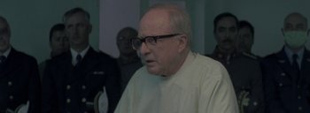 Movie still from “Post Mortem” (2010), directed by Pablo Larraín – An older man wearing glasses and a white shirt; Close Up shot, Over the shoulder angle