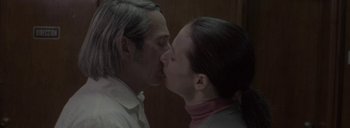 Movie still from “Post Mortem” (2010), directed by Pablo Larraín – A man and a woman kissing each other in front of a wooden wall; Close Up shot, Low angle