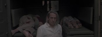 Movie still from “Post Mortem” (2010), directed by Pablo Larraín – A man in a white shirt is in a room; Close Up shot, Over the shoulder angle