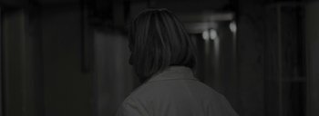 Movie still from “Post Mortem” (2010), directed by Pablo Larraín – A person with a white shirt is looking at something in the dark; Close Up shot, Over the shoulder angle