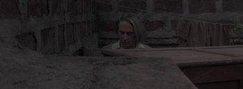 Movie still from “Post Mortem” (2010), directed by Pablo Larraín – A man with long blonde hair looking down at the ground; Medium shot, Low angle