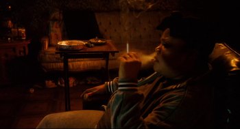 Movie still from “Precious” (2009), directed by Lee Daniels – A man sitting in a chair smoking a cigarette; Medium shot, High angle