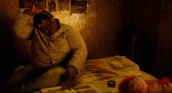 Movie still from “Precious” (2009), directed by Lee Daniels – A woman sitting on a bed in a room; Medium shot, High angle