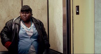 Movie still from “Precious” (2009), directed by Lee Daniels – A woman standing next to an elevator in a building; Medium shot, High angle