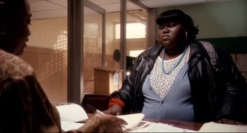 Movie still from “Precious” (2009), directed by Lee Daniels – A woman sitting at a table writing on a piece of paper; Medium shot, Over the shoulder angle