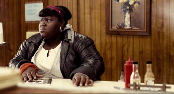 Movie still from “Precious” (2009), directed by Lee Daniels – A woman sitting at a table in front of a painting; Medium shot, Over the shoulder angle