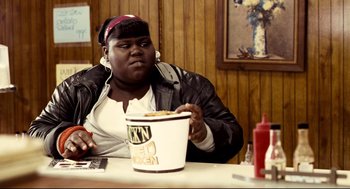 Movie still from “Precious” (2009), directed by Lee Daniels – A person sitting at a table with a bowl of food; Medium shot, Over the shoulder angle