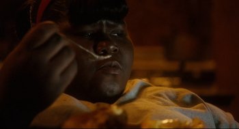 Movie still from “Precious” (2009), directed by Lee Daniels – A man eating food while sitting on a bed; Extreme Close Up shot, High angle