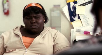 Movie still from “Precious” (2009), directed by Lee Daniels – A woman with a orange headband sitting in front of a wall; Close Up shot, Over the shoulder angle