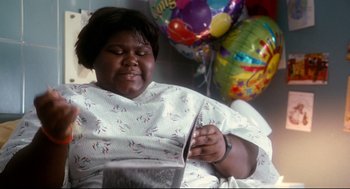 Movie still from “Precious” (2009), directed by Lee Daniels – A woman sitting in a hospital bed with balloons in the background; Medium shot, High angle