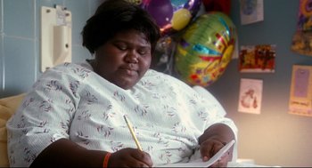 Movie still from “Precious” (2009), directed by Lee Daniels – A woman sitting in front of balloons writing on a note pad; Close Up shot, High angle