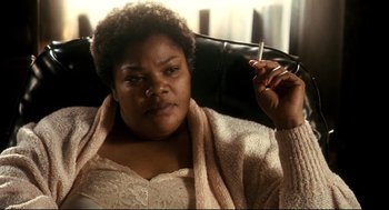 Movie still from “Precious” (2009), directed by Lee Daniels – A woman sitting in a chair holding a cigarette in her hand; Close Up shot, High angle