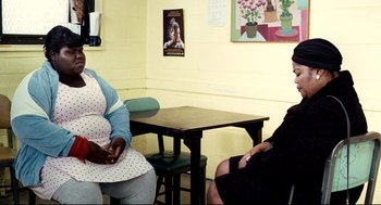 Movie still from “Precious” (2009), directed by Lee Daniels – Two women sitting at a table in front of a painting; Medium shot, Over the shoulder angle