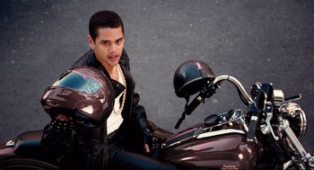 Movie still from “Precious” (2009), directed by Lee Daniels – A man sitting on the back of a brown motorcycle; Medium shot, High angle
