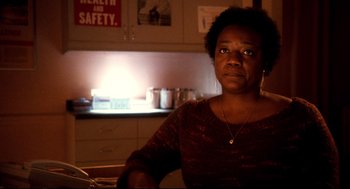 Movie still from “Precious” (2009), directed by Lee Daniels – A woman sitting at a table in a dark room; Close Up shot, Low angle