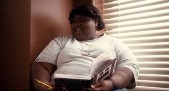 Movie still from “Precious” (2009), directed by Lee Daniels – A woman sitting in front of a window holding a book; Close Up shot, High angle