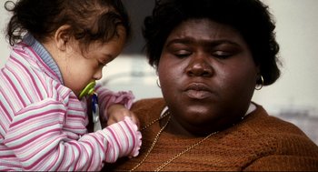 Movie still from “Precious” (2009), directed by Lee Daniels – A young girl is holding a pair of shears near a woman; Close Up shot, High angle