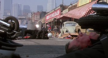 Movie still from “Predator 2” (1990), directed by Stephen Hopkins – A street scene with a person laying on the ground; Wide shot, High angle