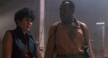 Movie still from “Predator 2” (1990), directed by Stephen Hopkins – A man and a woman standing next to each other; Medium shot, Low angle