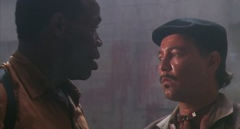 Movie still from “Predator 2” (1990), directed by Stephen Hopkins – Two men standing next to each other in front of a brick wall; Close Up shot, Low angle