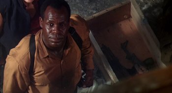 Movie still from “Predator 2” (1990), directed by Stephen Hopkins – A man in a brown shirt is looking at the camera; Close Up shot, Low angle