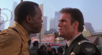 Movie still from “Predator 2” (1990), directed by Stephen Hopkins – Two men face each other on a city street; Close Up shot, Low angle
