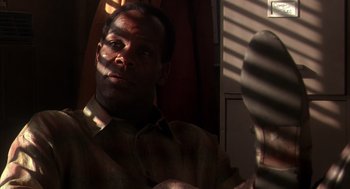 Movie still from “Predator 2” (1990), directed by Stephen Hopkins – A man is looking into a mirror in a room; Close Up shot, Low angle