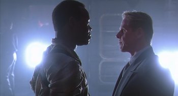 Movie still from “Predator 2” (1990), directed by Stephen Hopkins – Two men are facing each other in a dark room; Close Up shot, Low angle