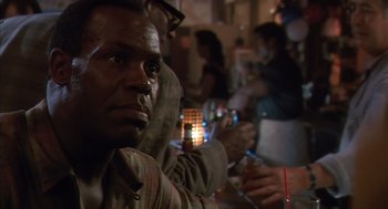 Movie still from “Predator 2” (1990), directed by Stephen Hopkins – A person sitting at a table; Close Up shot, Over the shoulder angle