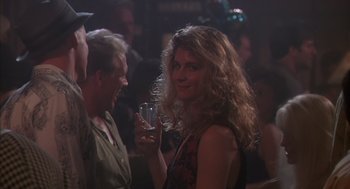 Movie still from “Predator 2” (1990), directed by Stephen Hopkins – A woman is holding a glass of wine in her right hand; Close Up shot, Over the shoulder angle