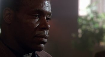 Movie still from “Predator 2” (1990), directed by Stephen Hopkins – A man's face in a dark room; Close Up shot, Low angle