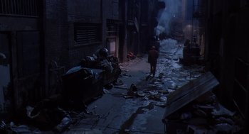 Movie still from “Predator 2” (1990), directed by Stephen Hopkins – A man walking down a street near a pile of trash; Extreme Wide shot, High angle