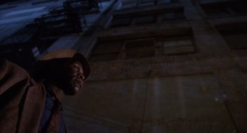 Movie still from “Predator 2” (1990), directed by Stephen Hopkins – A man with a hat on standing in front of a building; Medium shot, Low angle
