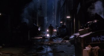 Movie still from “Predator 2” (1990), directed by Stephen Hopkins – A man walking down a street at night with trash everywhere; Extreme Wide shot, Low angle
