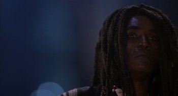 Movie still from “Predator 2” (1990), directed by Stephen Hopkins – A man with dreads is looking into the distance; Close Up shot, Low angle