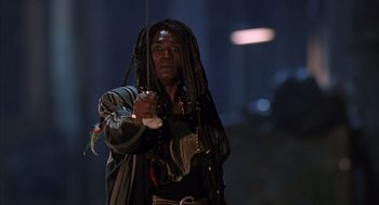 Movie still from “Predator 2” (1990), directed by Stephen Hopkins – A man with dreadlocks is holding a bow and arrow; Medium shot, Low angle