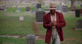 Movie still from “Predator 2” (1990), directed by Stephen Hopkins – A man standing in front of a grave in a cemetery; Medium shot, Low angle