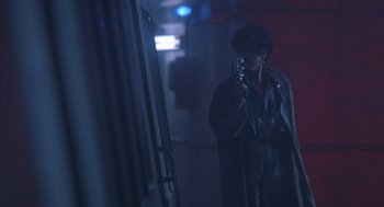 Movie still from “Predator 2” (1990), directed by Stephen Hopkins – A person holding a microphone in a dark room; Medium shot, Low angle