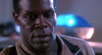 Movie still from “Predator 2” (1990), directed by Stephen Hopkins – A man's face with a blurry background; Close Up shot, Low angle