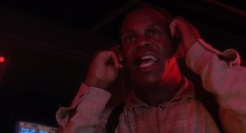 Movie still from “Predator 2” (1990), directed by Stephen Hopkins – A man with headphones is smiling for the camera; Close Up shot, Low angle