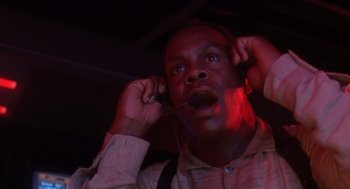 Movie still from “Predator 2” (1990), directed by Stephen Hopkins – A man with headphones is looking up at the ceiling; Close Up shot, Low angle