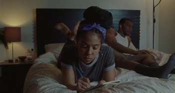 A woman is lying on a bed writing in a notebook