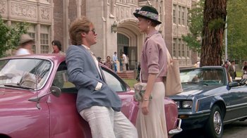 Movie still from “Pretty in Pink” (1986), directed by Howard Deutch – A man and a woman sitting next to each other on the side of a car; Wide shot, Low angle