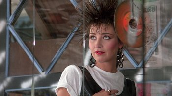 Movie still from “Pretty in Pink” (1986), directed by Howard Deutch – A woman with a mohawk is standing in front of a mirror; Close Up shot, Over the shoulder angle