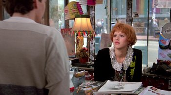 Movie still from “Pretty in Pink” (1986), directed by Howard Deutch – A woman sitting in front of a table in front of a lamp; Medium shot, Over the shoulder angle