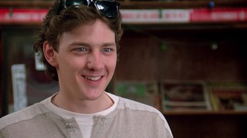 Movie still from “Pretty in Pink” (1986), directed by Howard Deutch – A young man wearing sunglasses and smiling for the camera; Close Up shot, Low angle