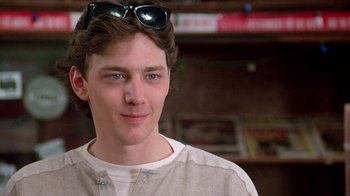 Movie still from “Pretty in Pink” (1986), directed by Howard Deutch – A young man wearing a pair of sun glasses; Close Up shot, Low angle