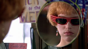 Movie still from “Pretty in Pink” (1986), directed by Howard Deutch – A woman wearing sunglasses looking into a mirror; Close Up shot, Over the shoulder angle