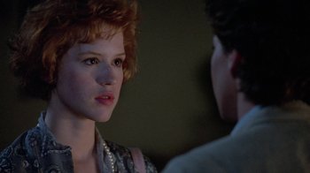 Movie still from “Pretty in Pink” (1986), directed by Howard Deutch – A woman with red hair and a pearl necklace talking to a man in a suit; Close Up shot, Over the shoulder angle